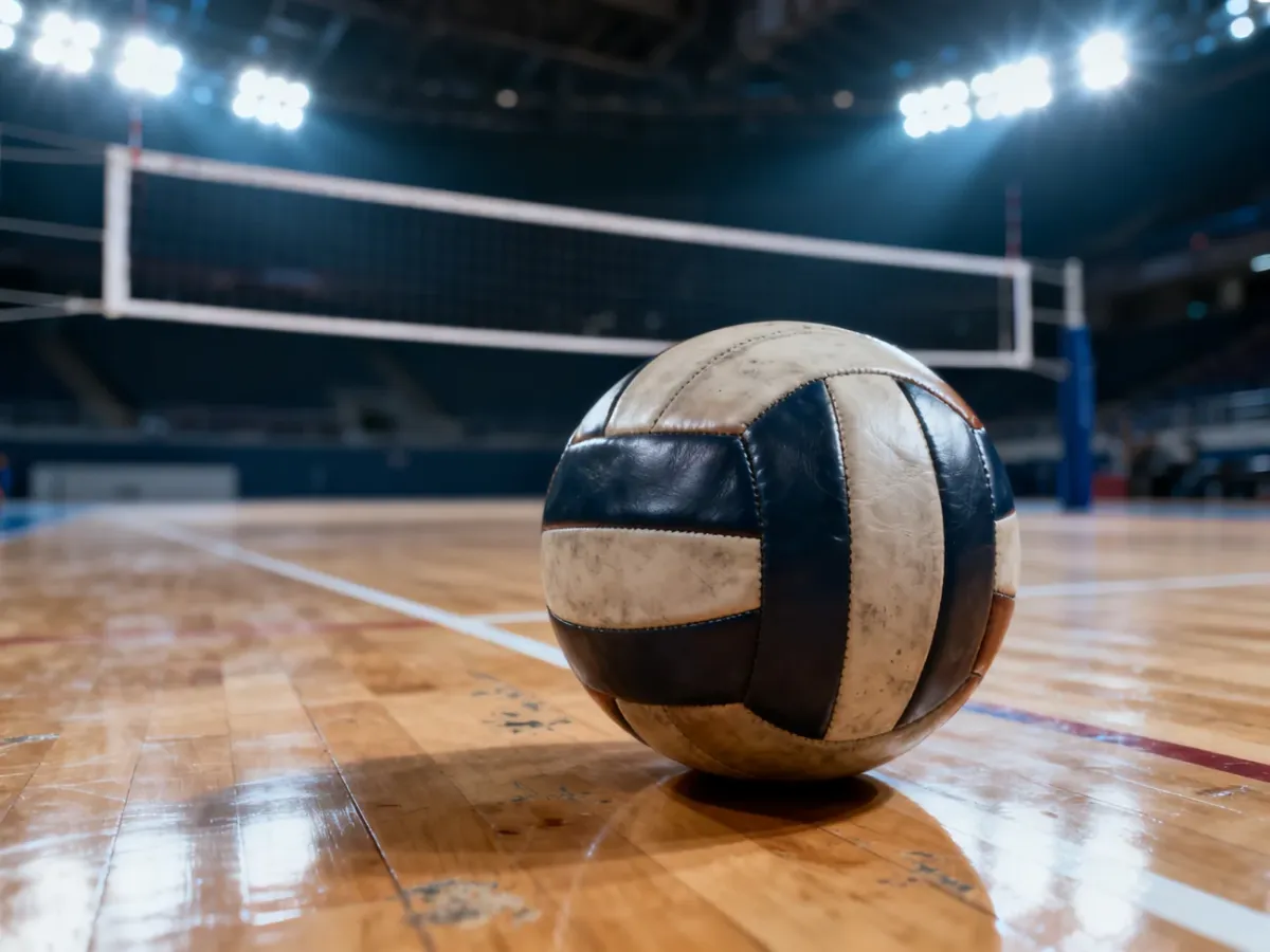 Skórzana piłka do siatkówki na parkiecie hali sportowej z rozmytą siatką w tle.